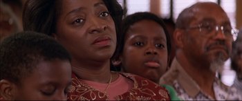 Movie still from “A Time to Kill” (1996), directed by Joel Schumacher – A woman sitting next to a child in a room; Close Up shot, Over the shoulder angle