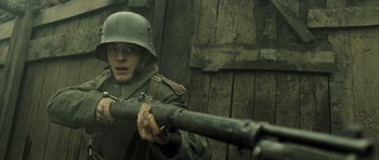 Movie still from “A Very Long Engagement” (2004), directed by Jean-Pierre Jeunet – A man in a military uniform holding a gun; Close Up shot, Low angle