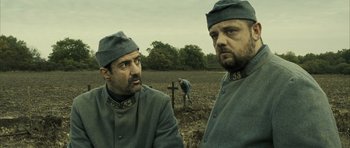 Movie still from “A Very Long Engagement” (2004), directed by Jean-Pierre Jeunet – Two men dressed in military uniforms in a field; Medium shot, Over the shoulder angle