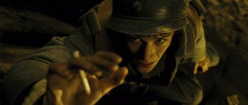 Movie still from “A Very Long Engagement” (2004), directed by Jean-Pierre Jeunet – A man wearing a hat is holding a cigarette; Close Up shot, High angle