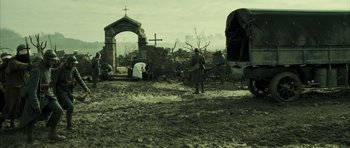 Movie still from “A Very Long Engagement” (2004), directed by Jean-Pierre Jeunet – A group of people standing in a dirt field near an old church; Extreme Wide shot, High angle