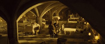 Movie still from “A Very Long Engagement” (2004), directed by Jean-Pierre Jeunet – Two people sitting at a table in a room; Wide shot, High angle