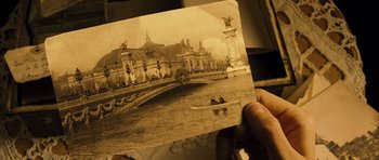 Movie still from “A Very Long Engagement” (2004), directed by Jean-Pierre Jeunet – An old photo of a bridge with a boat in the water; Extreme Close Up shot, High angle