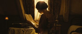 Movie still from “A Very Long Engagement” (2004), directed by Jean-Pierre Jeunet – A woman is reading a book in the sunlight; Medium shot, High angle