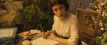 Movie still from “A Very Long Engagement” (2004), directed by Jean-Pierre Jeunet – A young woman sitting at a table writing on a piece of paper; Close Up shot, High angle