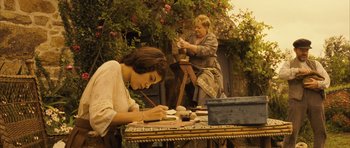 Movie still from “A Very Long Engagement” (2004), directed by Jean-Pierre Jeunet – Two women are painting in a garden setting; Wide shot, Low angle