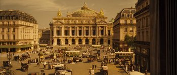 Movie still from “A Very Long Engagement” (2004), directed by Jean-Pierre Jeunet – An old picture of an old city with cars parked in front of a building; Extreme Wide shot, High angle