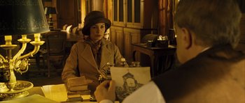 Movie still from “A Very Long Engagement” (2004), directed by Jean-Pierre Jeunet – A woman sitting at a table in a room; Medium shot, Over the shoulder angle