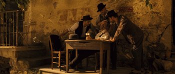 Movie still from “A Very Long Engagement” (2004), directed by Jean-Pierre Jeunet – A group of men standing around a wooden table; Wide shot, Low angle