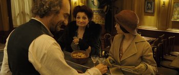 Movie still from “A Very Long Engagement” (2004), directed by Jean-Pierre Jeunet – A group of people sitting at a table with food; Medium shot, Over the shoulder angle