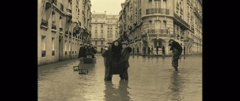 Movie still from “A Very Long Engagement” (2004), directed by Jean-Pierre Jeunet – Two people are standing in a flooded street; Wide shot, High angle