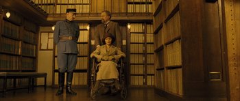 Movie still from “A Very Long Engagement” (2004), directed by Jean-Pierre Jeunet – A woman sitting in a wheel chair in front of two men; Wide shot, Low angle