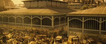 Movie still from “A Very Long Engagement” (2004), directed by Jean-Pierre Jeunet – An antique market in an old building with a lot of cars parked around it; Extreme Wide shot, High angle