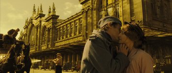 Movie still from “A Very Long Engagement” (2004), directed by Jean-Pierre Jeunet – A man and a woman kissing in front of a building; Wide shot, Low angle