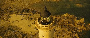 Movie still from “A Very Long Engagement” (2004), directed by Jean-Pierre Jeunet – An aerial view of a light house on the beach; Extreme Wide shot, High angle