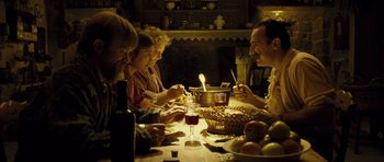 Movie still from “A Very Long Engagement” (2004), directed by Jean-Pierre Jeunet – A group of people sitting at a table with food; Medium shot, High angle