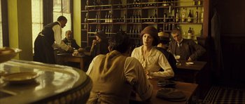 Movie still from “A Very Long Engagement” (2004), directed by Jean-Pierre Jeunet – A group of people sitting at a table in a room; Medium shot, Over the shoulder angle