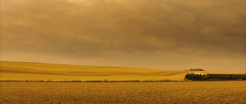 Movie still from “A Very Long Engagement” (2004), directed by Jean-Pierre Jeunet – A large field with a cloudy sky in the background; Extreme Wide shot, High angle
