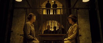 Movie still from “A Very Long Engagement” (2004), directed by Jean-Pierre Jeunet – A group of people standing in front of a jail cell; Wide shot, Low angle