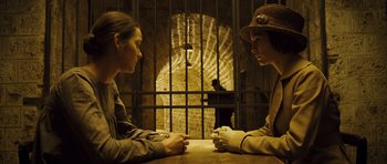 Movie still from “A Very Long Engagement” (2004), directed by Jean-Pierre Jeunet – Two people sitting at a table in a jail cell; Medium shot, High angle