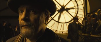 Movie still from “A Very Long Engagement” (2004), directed by Jean-Pierre Jeunet – A person wearing a hat near a clock tower; Close Up shot, Low angle