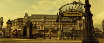 Movie still from “A Very Long Engagement” (2004), directed by Jean-Pierre Jeunet – A woman is standing in front of an old building; Extreme Wide shot, Low angle