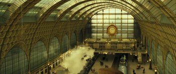 Movie still from “A Very Long Engagement” (2004), directed by Jean-Pierre Jeunet – A train station with a large clock on the wall; Extreme Wide shot, High angle