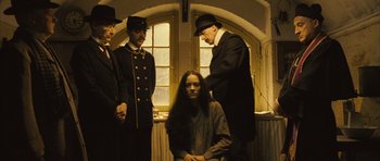 Movie still from “A Very Long Engagement” (2004), directed by Jean-Pierre Jeunet – A woman sitting in front of a group of men; Medium shot, Low angle