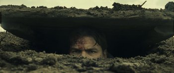Movie still from “A Very Long Engagement” (2004), directed by Jean-Pierre Jeunet – A man with blood on his face looking through a hole in the ground; Close Up shot, Low angle