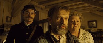Movie still from “A Very Long Engagement” (2004), directed by Jean-Pierre Jeunet – A man with a beard standing next to two other men; Medium shot, Low angle