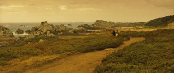 Movie still from “A Very Long Engagement” (2004), directed by Jean-Pierre Jeunet – Two people are walking on a dirt path near the ocean; Extreme Wide shot, High angle