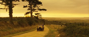 Movie still from “A Very Long Engagement” (2004), directed by Jean-Pierre Jeunet – An old car is driving down a dirt road; Extreme Wide shot, High angle