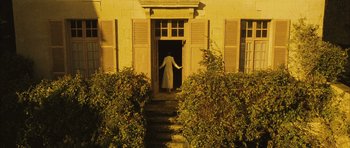 Movie still from “A Very Long Engagement” (2004), directed by Jean-Pierre Jeunet – A woman in a white coat standing in front of an open door; Extreme Wide shot, High angle