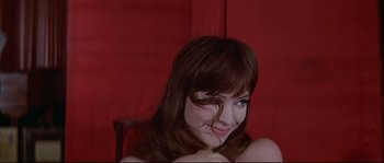 Movie still from “A Woman Is a Woman” (1961), directed by Jean-Luc Godard – A woman with long brown hair posing for a picture; Close Up shot, Over the shoulder angle