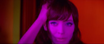Movie still from “A Woman Is a Woman” (1961), directed by Jean-Luc Godard – A woman's face in purple light; Close Up shot, Low angle