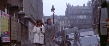 Movie still from “A Woman Is a Woman” (1961), directed by Jean-Luc Godard – A man and a woman walking down a street; Wide shot, Low angle