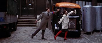 Movie still from “A Woman Is a Woman” (1961), directed by Jean-Luc Godard – A man and a woman walking on the street; Wide shot, Low angle