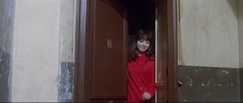 Movie still from “A Woman Is a Woman” (1961), directed by Jean-Luc Godard – A woman in a red shirt standing in front of a door; Medium shot, High angle