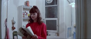 Movie still from “A Woman Is a Woman” (1961), directed by Jean-Luc Godard – A woman in a red shirt is reading a book; Medium shot, Low angle