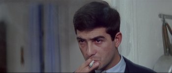 Movie still from “A Woman Is a Woman” (1961), directed by Jean-Luc Godard – A man with a cigarette in his mouth; Close Up shot, Low angle