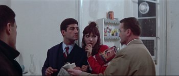 Movie still from “A Woman Is a Woman” (1961), directed by Jean-Luc Godard – A group of people standing next to each other in a room; Medium shot, Over the shoulder angle
