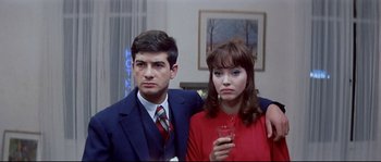 Movie still from “A Woman Is a Woman” (1961), directed by Jean-Luc Godard – A man and a woman standing next to each other holding a wine glass; Medium shot, High angle