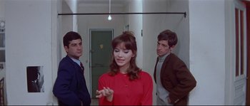 Movie still from “A Woman Is a Woman” (1961), directed by Jean-Luc Godard – A group of people standing in a room; Medium shot, Over the shoulder angle