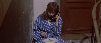 Movie still from “A Woman Is a Woman” (1961), directed by Jean-Luc Godard – A woman sitting on the floor talking on the phone; Medium shot, High angle