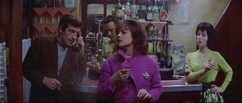 Movie still from “A Woman Is a Woman” (1961), directed by Jean-Luc Godard – A group of people standing around in a bar; Medium shot, Over the shoulder angle