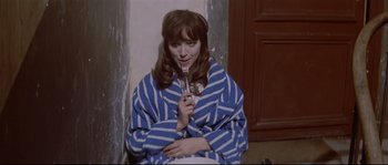 Movie still from “A Woman Is a Woman” (1961), directed by Jean-Luc Godard – A woman holding a fork in her mouth; Medium shot, High angle
