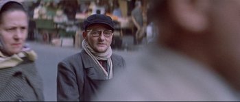 Movie still from “A Woman Is a Woman” (1961), directed by Jean-Luc Godard – An older man wearing glasses and a hat; Close Up shot, Over the shoulder angle