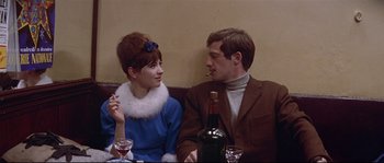 Movie still from “A Woman Is a Woman” (1961), directed by Jean-Luc Godard – A man and a woman sitting at a dinner table; Medium shot, Over the shoulder angle