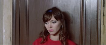Movie still from “A Woman Is a Woman” (1961), directed by Jean-Luc Godard – A woman with long brown hair wearing a red shirt; Close Up shot, High angle