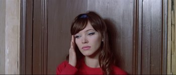 Movie still from “A Woman Is a Woman” (1961), directed by Jean-Luc Godard – A woman in a red shirt is holding her hand up to her face; Close Up shot, High angle